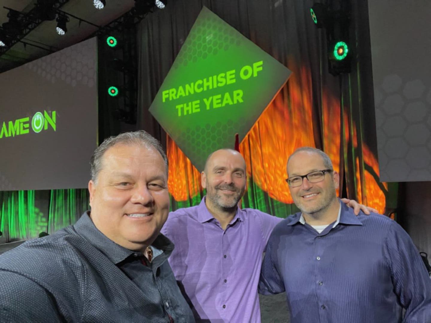3 men posing in front of franchise of the year sign