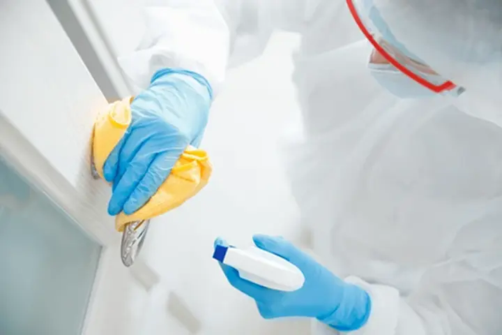 a person spraying and wiping down a wall